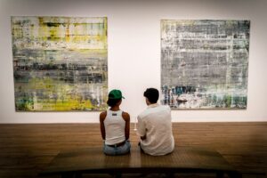 a man and a woman sitting on a bench in front of paintings