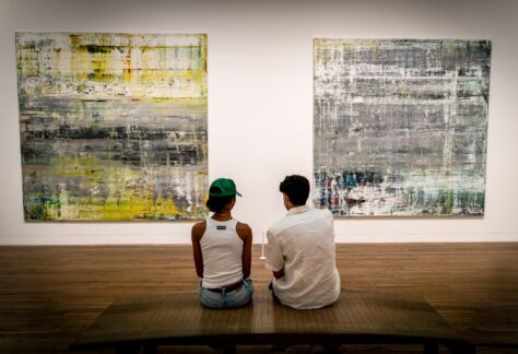 a man and a woman sitting on a bench in front of paintings