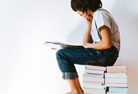 woman in gray t-shirt and blue denim jeans reading book